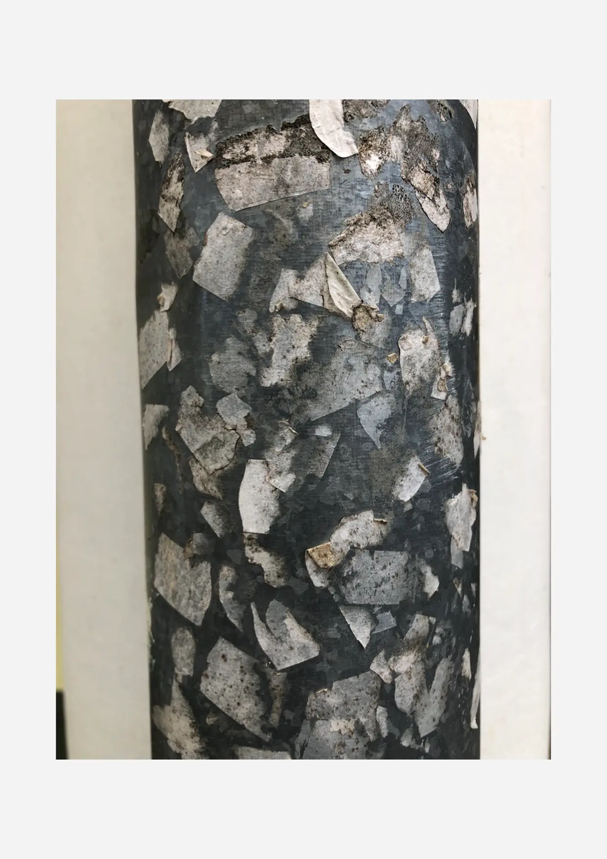 A weathered column covered with layers of adhesive material.